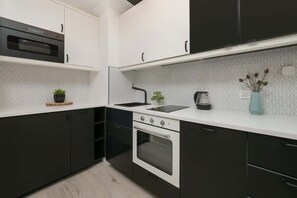 A modern kitchen with black and white cabinetry, a built-in oven, and a sleek white backsplash.

