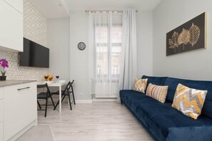 Another angle of the living room, showing the blue sofa, decorative pillows, and a bright window adding charm to the space.

