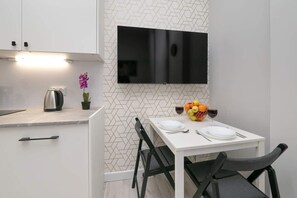 A cozy dining nook with a mounted TV, a small dining table, and elegant decor elements creating a welcoming space.

