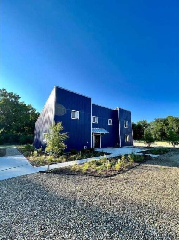 Front view of home, driveway, and gardens.