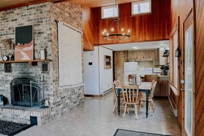 Exposed brick fireplace and open-concept kitchen and dining space. 