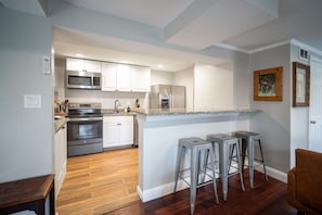 Modern kitchen with bar seating, granite countertops, and sleek stainless appliances!