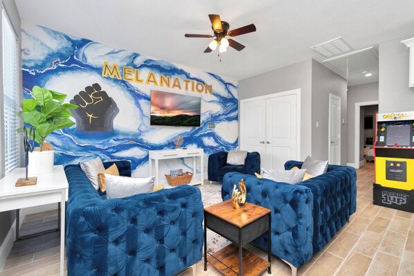 MelaNation! Living Room with 3 seater sofa, single couches and 75 inch TV