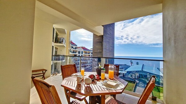 Escape to Sunset Bay, Ponta da Cruz, Funchal. Capture tranquility on the expansive balcony with ocean vistas, a hint of mountains, and a charming outdoor breakfast arrangement. #balcony #oceanview #centromar