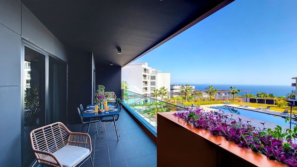 Experience seaside serenity at Roots Loft: a charming apartment with a big balcony, outdoor furniture, ocean views, and a refreshing poolside panorama. #balcony #oceanview #outdoorfurniture