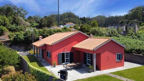 Captured from above, Casa Dasa unveils its vibrant red painting amidst lush greenery. Aerial serenity meets traditional charm, offering a glimpse of tranquility and ocean views in Santa, Porto Moniz