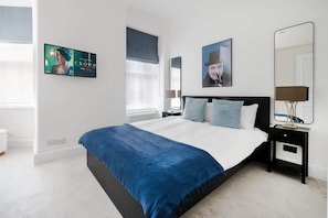 Elegant bedroom with king bed, Smart TV, air conditioning & dedicated desk area.