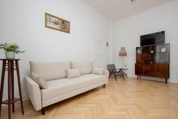 A bright living room with a beige sofa, a classic wooden coffee table, and elegant decor, featuring parquet flooring and soft lighting.

