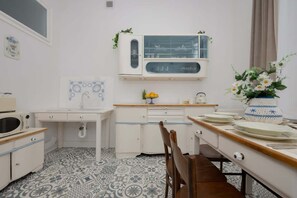 A stylish kitchen with vintage-inspired cabinetry, a wooden dining table, and decorative details, blending classic and modern elements.

