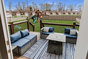 Relax on the deck with comfy seating, fire table, and views of the playset.