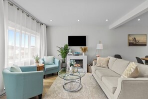 Cozy living room vibes! Relax in style by the modern fireplace, sink into plush seating, and soak up the serene ambiance for the ultimate unwind.