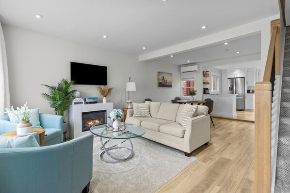 Relax in this stylish living space featuring a cozy fireplace, sleek furniture, and an inviting open-concept layout—perfect for unwinding or entertaining!