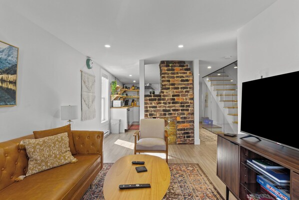 Brick & Chic: Relax in a cozy living room with a warm leather sofa, rustic charm, and stylish open design—your perfect getaway spot awaits!