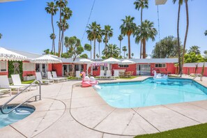 Dive into this stunning heated pool, surrounded by lush palm trees and a vibrant pink house.