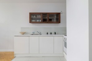 Kitchenette with an electric hob, oven, refrigerator with freezer, electric kettle, washing machine and table with 2 chairs