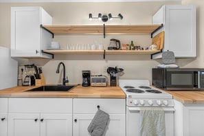 Fully Equipped Kitchen With Butcher Block Countertops And Stylish Open Shelving