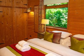 double bedroom with cushions and throws, window, curtains, folded towels on bed