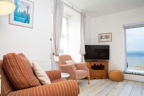 Sitting room with two armchairs, foot stool and TV