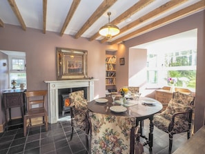 Dining area with round table and four fabric covered chairs. Fireplace with woodburner