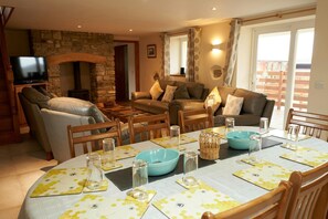 Dining area with table and chairs, lounge with fireplace and TV