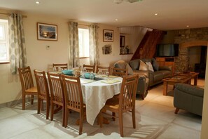 Dining area with table and chairs, lounge area and stairs to first floor