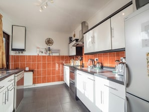 Drifwood kitchen with white floor and wall units, upright fridge/freezer and tiles floor and walls