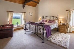 King sized bed with bedside cabinets and lamps, armchair and rug on the floor