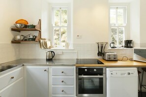 Kitchen with two windows, cooker, sink and microwave