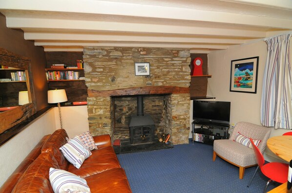 Living room with leather sofa, armchair and fireplace. TV on stand.
