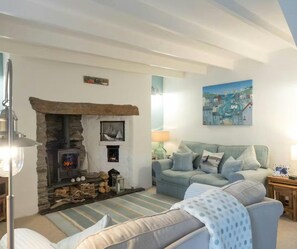 Living room with two sofas, fireplace with wooden beam, woodburner, tv