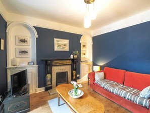 Large red sofa, coffee table and TV. Original alcoves and picture rails