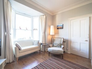 Sofa and arm chair. Stripped rug on wooden floor