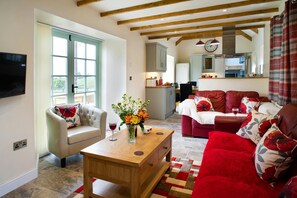 Sitting room with sofas, armchair, coffee table, french doors to garden