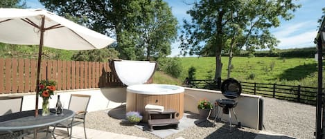 Patio with table, chairs, parasol and hot tub
