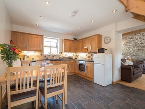 Kitchen in Briallen with fitted units, table, chairs, fridge and window