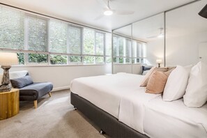 The primary bedroom boasts a plush king-sized bed under the comfortable breeze of a ceiling fan.
