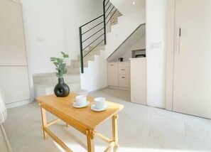 Cozy living-dining room with small table, kitchen and stairs to the bedroom.