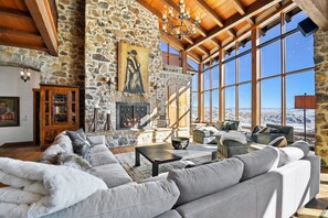 The main living area of Snow Pine at deer Valley, with a large sectional couch and armchairs surrounding a fireplace.