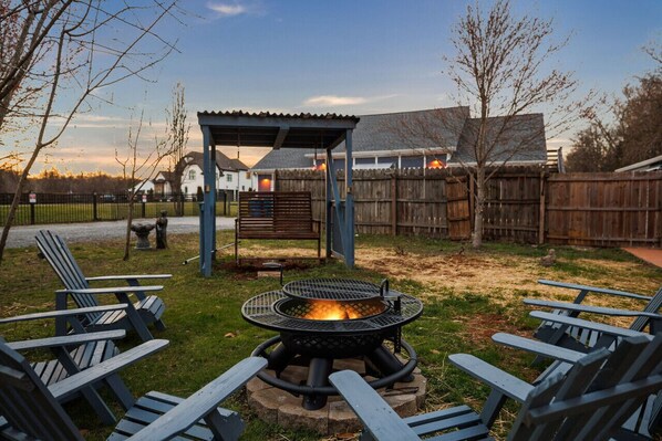 Firepit/grill with wooden adirondack chairs and porch swing. Amazing place to gather for smore's!