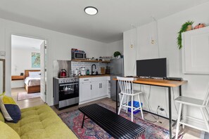 Cozy open-concept living space with a full kitchen, workspace, and a comfy bedroom.