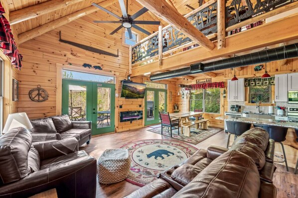 The gorgeous living room includes high ceilings, a large Smart TV, fireplace, plenty of comfortable furniture and large windows that offer plenty of natural light.