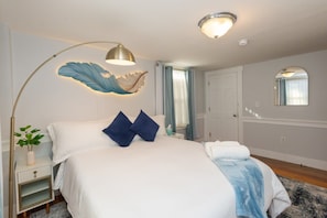 Unwind in this beautifully designed bedroom, where a cozy queen bed meets the soft glow of a feather-inspired light fixture. Your perfect retreat awaits!