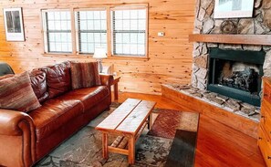 After a day of exploring Ruidoso, relax in the cozy living area featuring a plush leather couch and a charming stone fireplace. Enjoy the rustic décor and warm ambiance, perfect for relaxing.