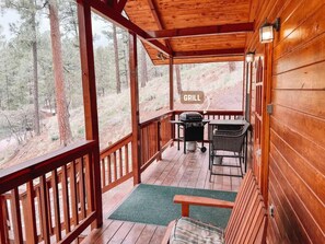 The comfort of this cozy deck with inviting seating and a ready-to-use grill is great for outdoor dining and relaxation, surrounded by the tranquil beauty of the Ruidoso mountains.