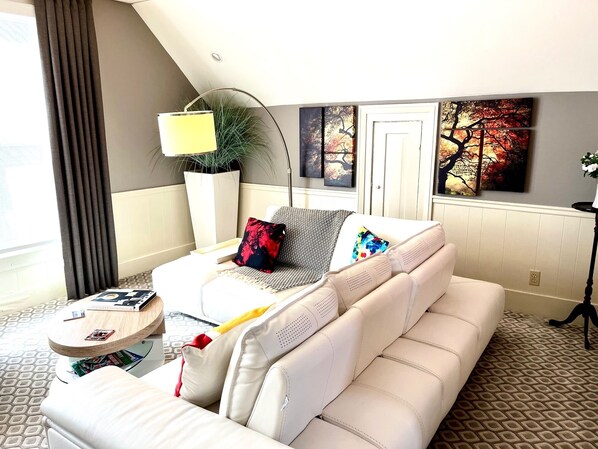 White Italian leather sectional sofa in living room with large windows 