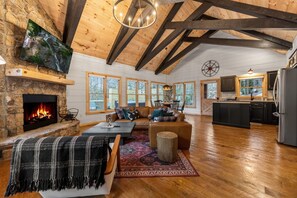 Step into our modern living space with high ceilings and sleek black beams. Chic furnishings blend style and comfort, while the open-concept layout connects seamlessly with the kitchen and dining area, offering a cozy yet contemporary retreat.