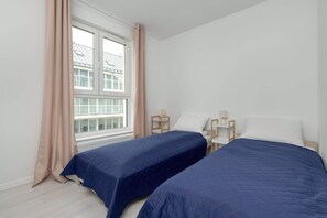 Another bright bedroom with twin beds, simple decor, and cozy blue bedding.