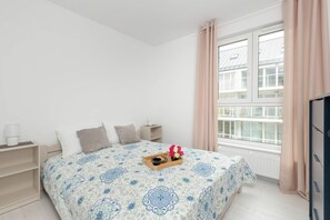 A bright and cozy bedroom with a plush double bed, soft bedding, and large windows that fill the room with natural light, creating a peaceful retreat.