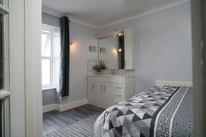 Double bedroom with bed, chest of drawers, mirror and window with sea views