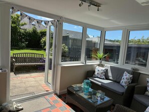 Conservatory with table and chairs and double doors leading to the garden